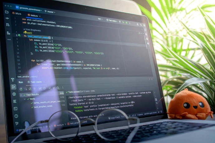 Laptop screen displaying code with glasses and plush toy.